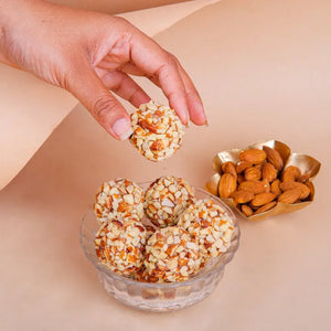 Badam Crunchy Ball pieces stacked on a white plate, representing the best gujarati sweets near me in Mota Varachha.