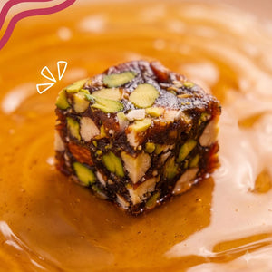 Close-up of a single Mithdi Black Date Bite drizzled with natural honey/syrup.